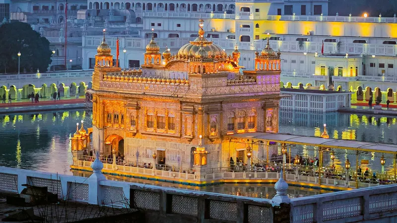 Harmandir Sahib lit at dusk, reflected in the surrounding sarovar