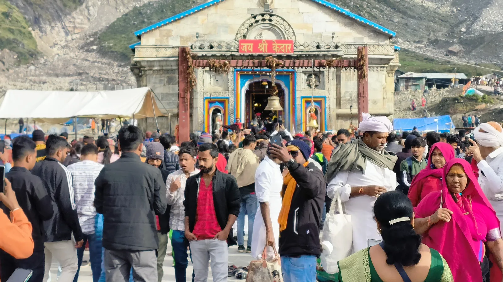 The Kedarnath temple with pilgrims gathered outside and snow peaks behind