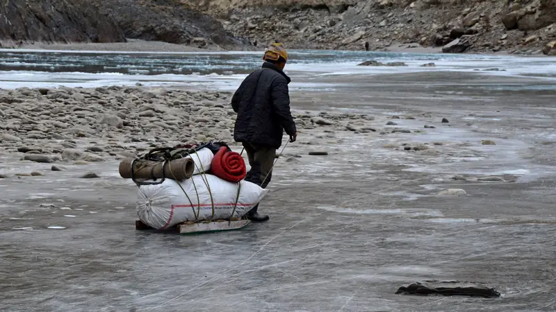 A trekker hauling a sled along the frozen Zanskar river gorge