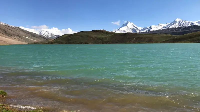 The turquoise water of Chandratal lake below Himalayan ridges