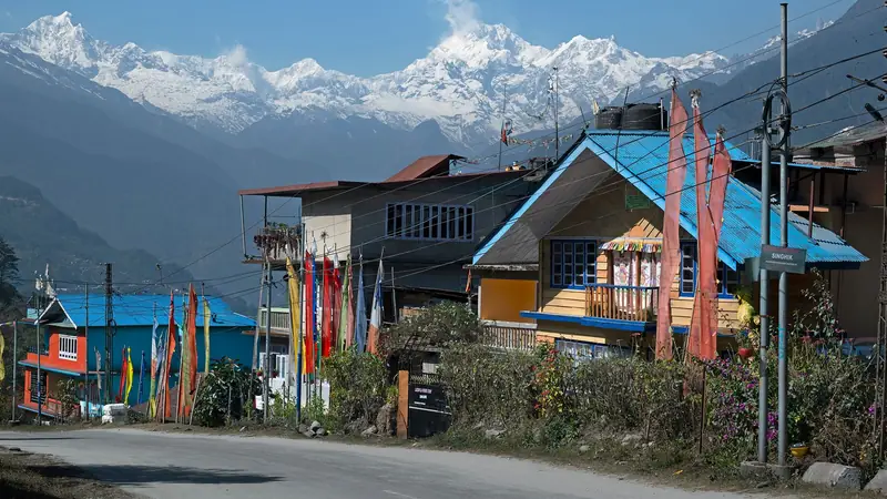 A Sikkim village street hung with prayer flags below snow peaks