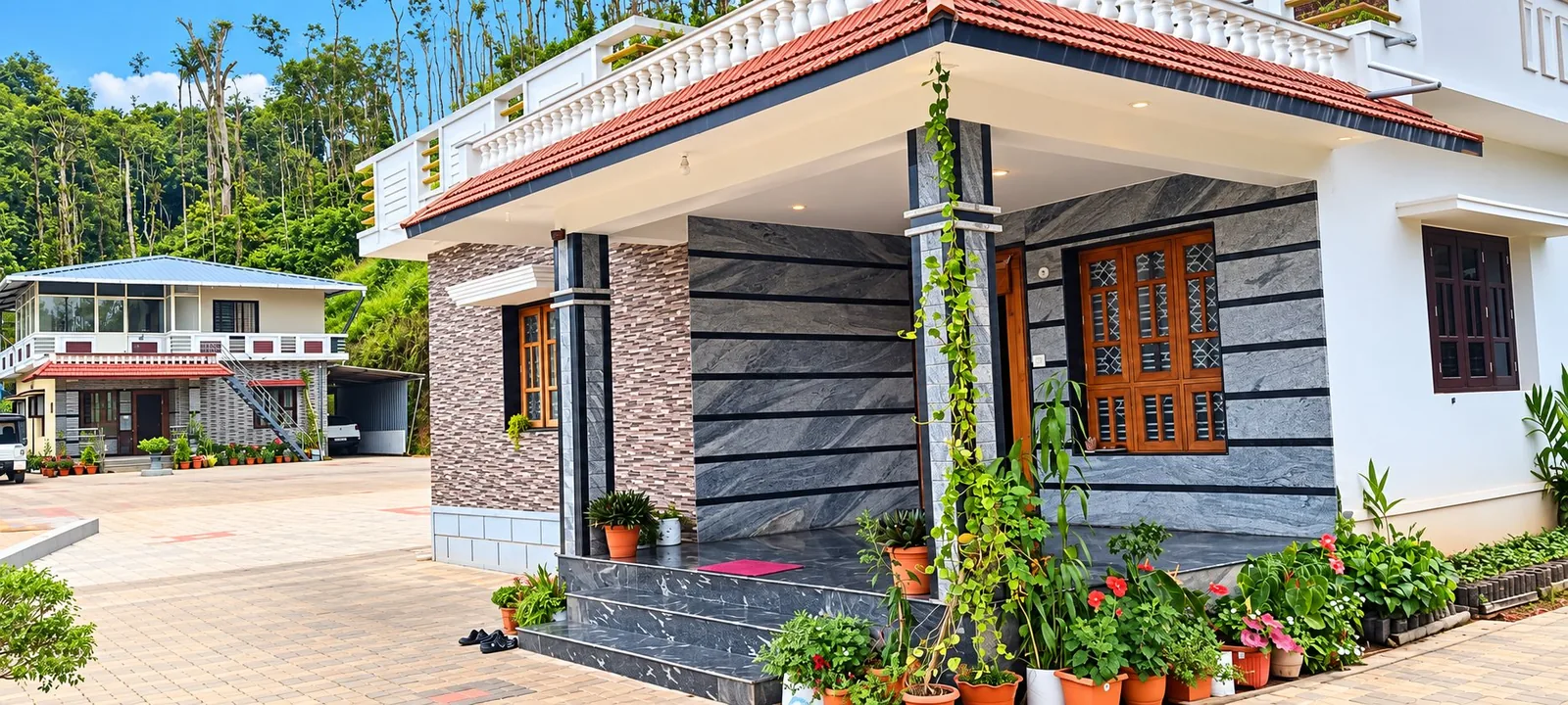 The Golden Hills homestay: a two-storey house with a tiled porch roof on polished granite pillars, a first-floor terrace, and a paved forecourt with potted plants
